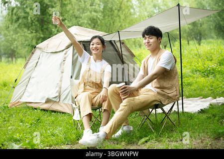 un jeune couple reposant sur des chaises pliantes, de l'eau potable et du café Banque D'Images