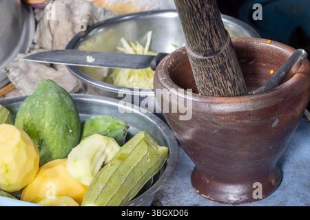 Une installation de cuisine thaïlandaise traditionnelle avec des légumes frais, un mortier et un pilon sur un comptoir de cuisine pour la préparation de la salade de papaye Banque D'Images