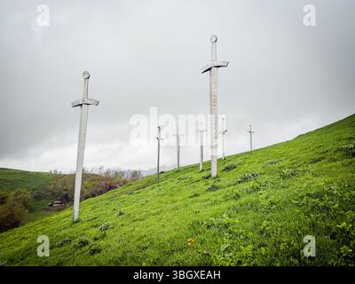 Tbilissi, Géorgie, Didgori, sculptures massives d'épée en métal s'élèvent d'une colline herbeuse sous un ciel sombre, formant un monument public frappant dans un Banque D'Images