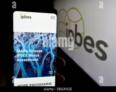 Stuttgart, Allemagne - 03-07-2025 : personne tenant un téléphone portable avec la page web de l'organisation intergouvernementale IPBES sur l'écran devant le logo. Banque D'Images