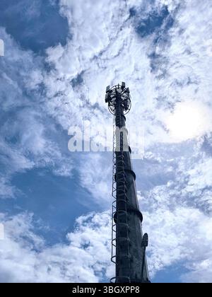 La tour de télécommunication est haute avec un fond de nuages blancs brillants et un ciel bleu Banque D'Images