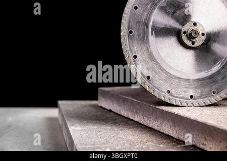 Lame de scie circulaire diamantée coupant les carreaux de béton fond noir Banque D'Images