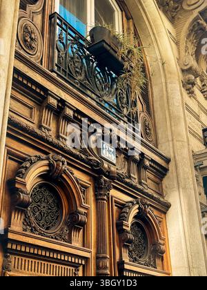 Une vue rapprochée et en bas angle d'une porte en bois richement sculptée sur un bâtiment parisien historique, montrant des détails complexes, circulaire en fer forgé W. Banque D'Images