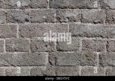 Vue détaillée d'un mur de briques altérées mettant en valeur sa texture robuste et ses imperfections naturelles, idéal pour une utilisation de fond ou de design. Photo d'arrière-plan Banque D'Images