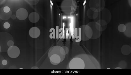 Image de taches lumineuses bokeh grises au-dessus d'un personnage effrayant rétroéclairé dans l'entrée de la porte au bout d'un couloir sombre Banque D'Images