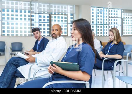 Groupe diversifié de professionnels de la santé participant à une conférence médicale, participant activement aux discussions et prenant des notes Banque D'Images