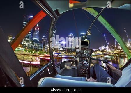 Pilotage d'hélicoptère en vol d'intérieur sur Elizabeth Quay Bridge by night sur Swan River à l'entrée de marina Quay Elizabeth. Vol panoramique au-dessus de Perth, nous Banque D'Images