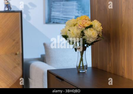 Élégant bouquet de pivoine artificielle dans un vase en verre sur des meubles modernes Banque D'Images