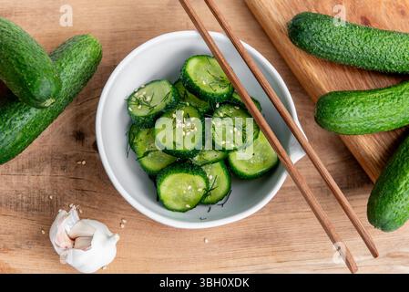 Sunomono, salade japonaise de concombre. Concombres tranchés avec vinaigrette asiatique de sauce soja, vinaigre de riz, huile de sésame, sucre et aneth dans un bol blanc sur bois ta Banque D'Images