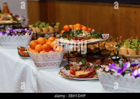 Un buffet de restauration magnifiquement arrangé présente une sélection de délicieux hors-d'œuvre, des fruits colorés et des décorations ornées sur une nappe blanche, ide Banque D'Images