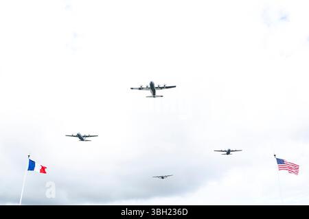 Des avions de la seconde Guerre mondiale volent au-dessus de leur tête lors de la cérémonie du cimetière américain de Normandie, Colleville-sur-mer, France, le 6 juin 2025. (Photo du DOD par le premier maître de 1re classe Alexander Kubitza de l'US Navy) Banque D'Images
