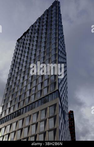 Vue rapprochée de la façade en verre complexe à motifs de losanges du bâtiment Pulse reflétant le paysage urbain animé d'Amsterdam. Banque D'Images