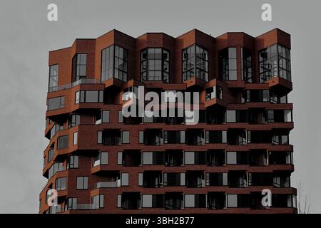 Une tour d'appartements en briques contemporaine unique à Zuidas, Amsterdam, présente un design géométrique audacieux, des fenêtres spectaculaires et des détails architecturaux saisissants. Banque D'Images
