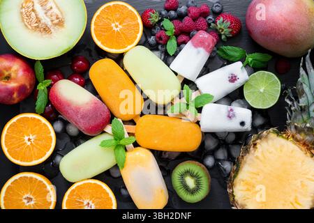 Au centre sur la variété de glaçons de sorbet et cônes de crème glacée près des ingrédients fruits et baies sur fond noir. Fraîcheur estivale de crème glacée et de cônes de sorbet. Horizontal. Vue de dessus. Banque D'Images