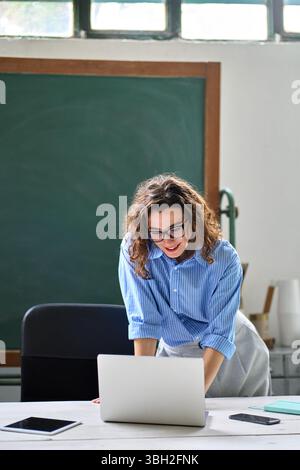 Jeune femme enseignante ou employée debout au bureau à l'aide d'un ordinateur portable. Banque D'Images