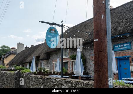 Le panneau Blue Door Restaurant devant les cottages traditionnels en chaume du XIXe siècle Banque D'Images