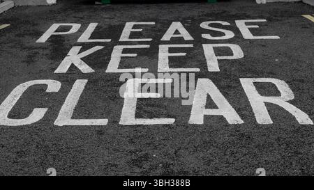 Vue aérienne d'un parking avec les mots « Please keep clear » marqués en blanc sur l'asphalte Banque D'Images