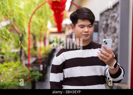 Jeune homme gay asiatique mignon dans le jardin zen de style chinois pendant la journée Banque D'Images