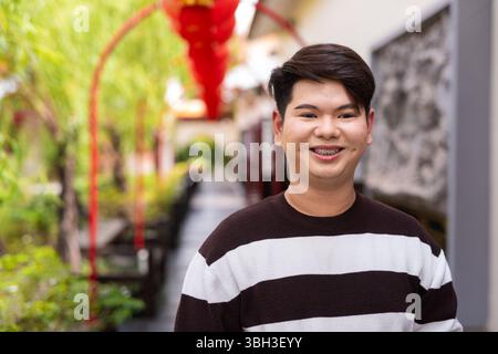Jeune homme gay asiatique mignon dans le jardin zen de style chinois pendant la journée Banque D'Images