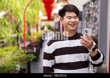 Jeune homme gay asiatique mignon dans le jardin zen de style chinois pendant la journée Banque D'Images