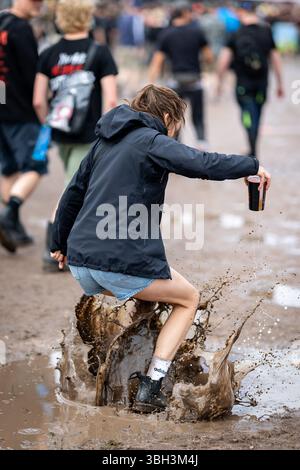 Nuremberg, Allemagne. 07 juin 2025. Un visiteur du festival en plein air « Rock im Park » saute dans une flaque d'eau. Crédit : Daniel Karmann/dpa/Alamy Live News Banque D'Images