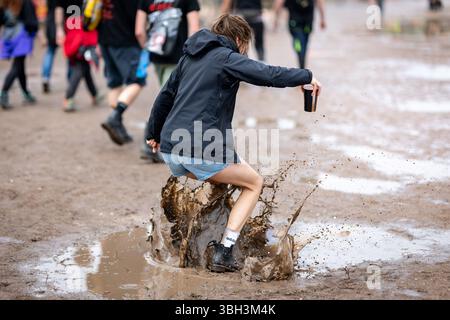 Nuremberg, Allemagne. 07 juin 2025. Un visiteur du festival en plein air « Rock im Park » saute dans une flaque d'eau. Crédit : Daniel Karmann/dpa/Alamy Live News Banque D'Images