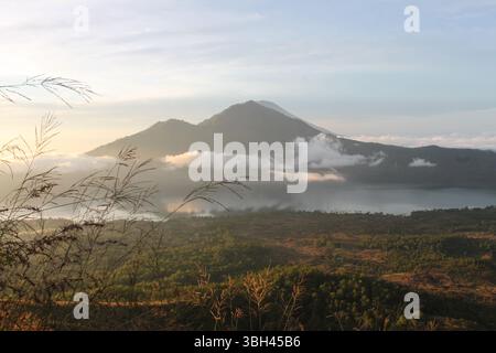 Volcan Mont Batur au lever du soleil avec brume sur le lac Batur, Bali, Indonésie Banque D'Images