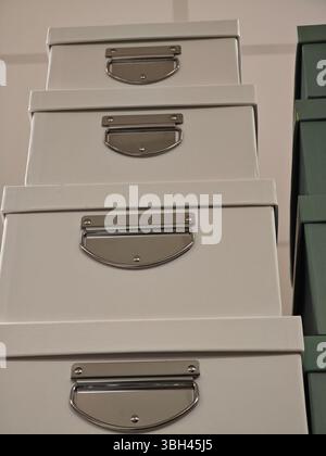 Quatre boîtes de rangement sont organisées en pile verticale, avec des surfaces lisses et claires et des poignées métalliques brillantes. L'arrière-plan indique un Banque D'Images