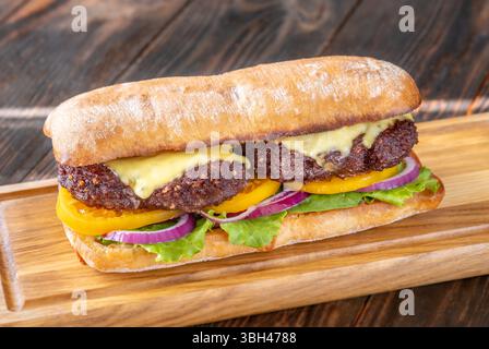 Sandwich en couches avec des ingrédients frais empilés haut sur la surface rustique de la planche à découper Banque D'Images