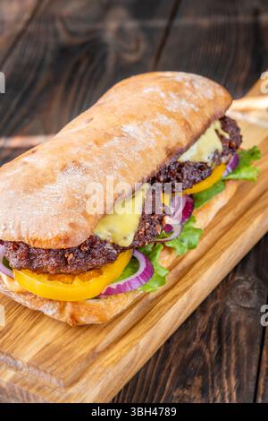 Sandwich en couches avec des ingrédients frais empilés haut sur la surface rustique de la planche à découper Banque D'Images