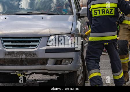 Trois pompiers ont ouvert une voiture après un accident lors d'une opération de sauvetage pour tirer le conducteur, qui est pris au piège et inconscient, hors de la voiture. Banque D'Images