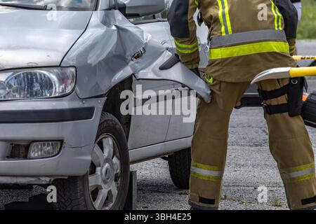 Trois pompiers ont ouvert une voiture après un accident lors d'une opération de sauvetage pour tirer le conducteur, qui est pris au piège et inconscient, hors de la voiture. Banque D'Images