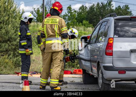 Trois pompiers ont ouvert une voiture après un accident lors d'une opération de sauvetage pour tirer le conducteur, qui est pris au piège et inconscient, hors de la voiture. Banque D'Images