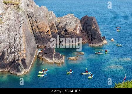 Kayak autour de la côte à Porthclais avec des grimpeurs sur les falaises, Pembrokeshire, pays de Galles, Royaume-Uni Banque D'Images