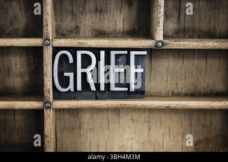Le mot CHAGRIN écrit en typographie métallique vintage dans un tiroir en bois avec des séparateurs Banque D'Images