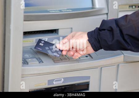 Une personne utilise une carte crypto Binance Visa pour retirer de l'argent d'un distributeur automatique. Concept de finance moderne, de paiements crypto-monnaie et de banque numérique. Banque D'Images