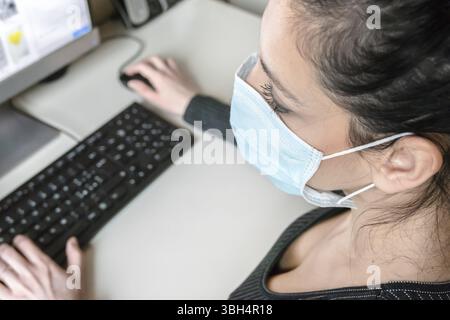 Jeune femme d'affaires travaillant à domicile portant un masque de protection. Coronavirus. Femme d'affaires en quarantaine pour coronavirus portant un masque de protection. Wor Banque D'Images