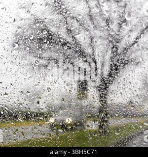 Silhouette voiture floue vu par gouttes d'eau sur le pare-brise de voiture Banque D'Images