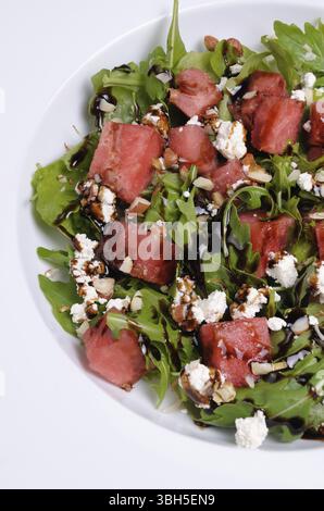 Salade de roquette, fromage ricotta avec tranches de pastèque, sauce soja balsamique Banque D'Images