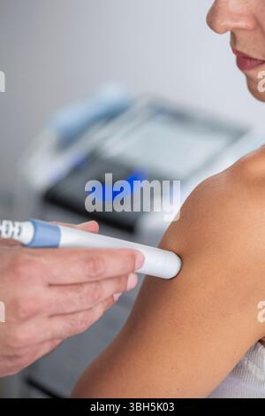 Physiothérapeute utilise la thérapie au laser sur l'épaule d'un patient pour soulager la douleur et favoriser la guérison. Le traitement se concentre sur l'amélioration de la réparation tissulaire et la réduction de l'inflammation. Banque D'Images