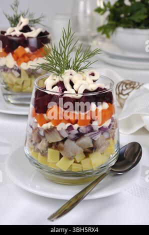 Salade de hareng haché avec les oignons, les pommes de terre, betteraves, carottes, assaisonné de sauce au yogourt dans un verre Banque D'Images