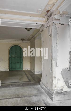Extérieur d'un vieil hôtel abandonné avec un mur de pelage et de la moisissure. Ancienne porte verte avec de vieux lustres au plafond Banque D'Images