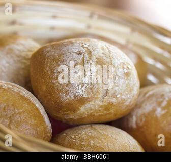 Gros plan d'osier rempli de petits pains. Produits de boulangerie frais sur table. DOF peu profond Banque D'Images