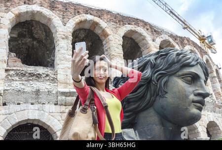 Jeune femme voyageuse faisant selfie photo avec l'arène à Vérone Italie sur fond. DOF peu profond Banque D'Images