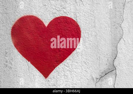 Main de coeur d'amour rouge dessinée sur le mur grungy. Fond texturé style de rue tendance Banque D'Images