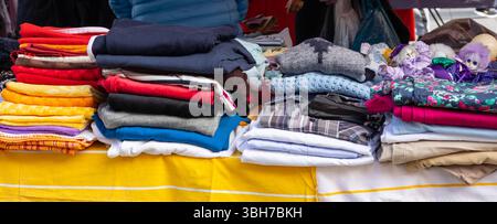 Une variété de vieux vêtements usés pulls et couvertures offerts sur un marché aux puces Banque D'Images