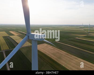 Vue aérienne d'une éolienne sur un champ agricole au coucher du soleil. Banque D'Images