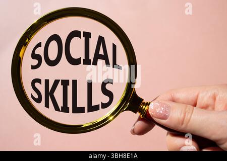 Symbole de compétences sociales. Mots conceptuels compétences sociales sur la loupe. Beau fond rose. Main d'homme d'affaires. Business and social Skills concept Banque D'Images