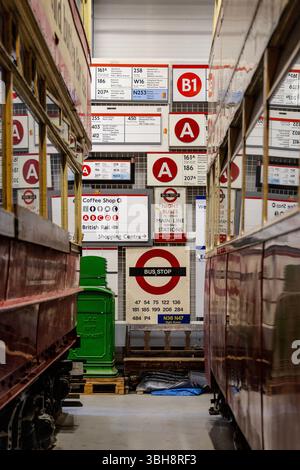 Collection de panneaux d'autobus entre deux voitures de tramway au London transport Museum Depot, Londres, Angleterre Banque D'Images