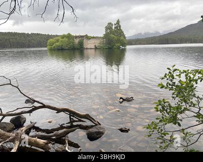 Promenade relaxante à travers les bois de Rothiemurchus jusqu'au paisible Loch an Eilein, avec un château en ruines encadré de pins anciens et de pics Cairngorm. Banque D'Images
